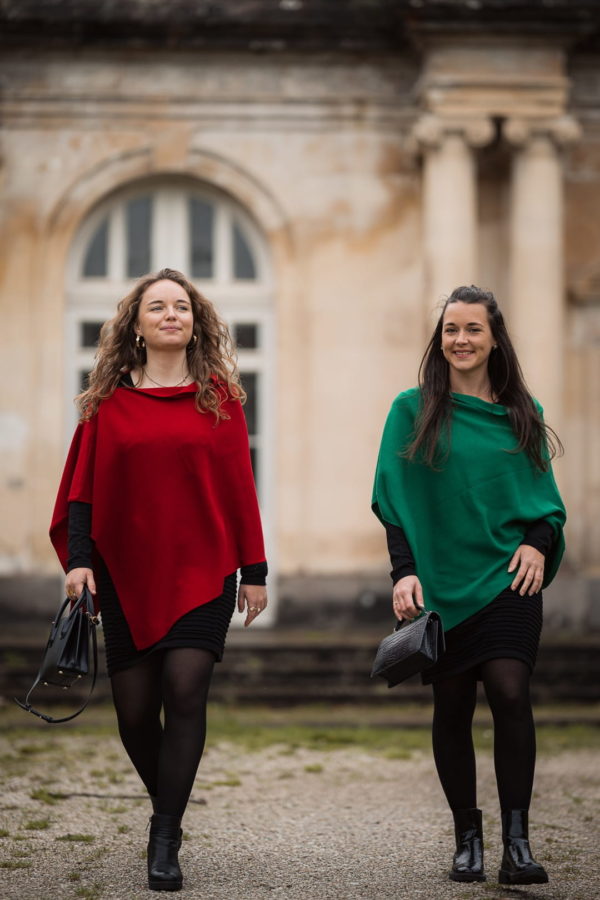 Ponchos en 100% mérinos extrafin portés par deux femmes marchant vers la caméra. La femme de gauche porte le ponch de couleur rouge et la femme de droite porte le poncho de couleur vert profond.