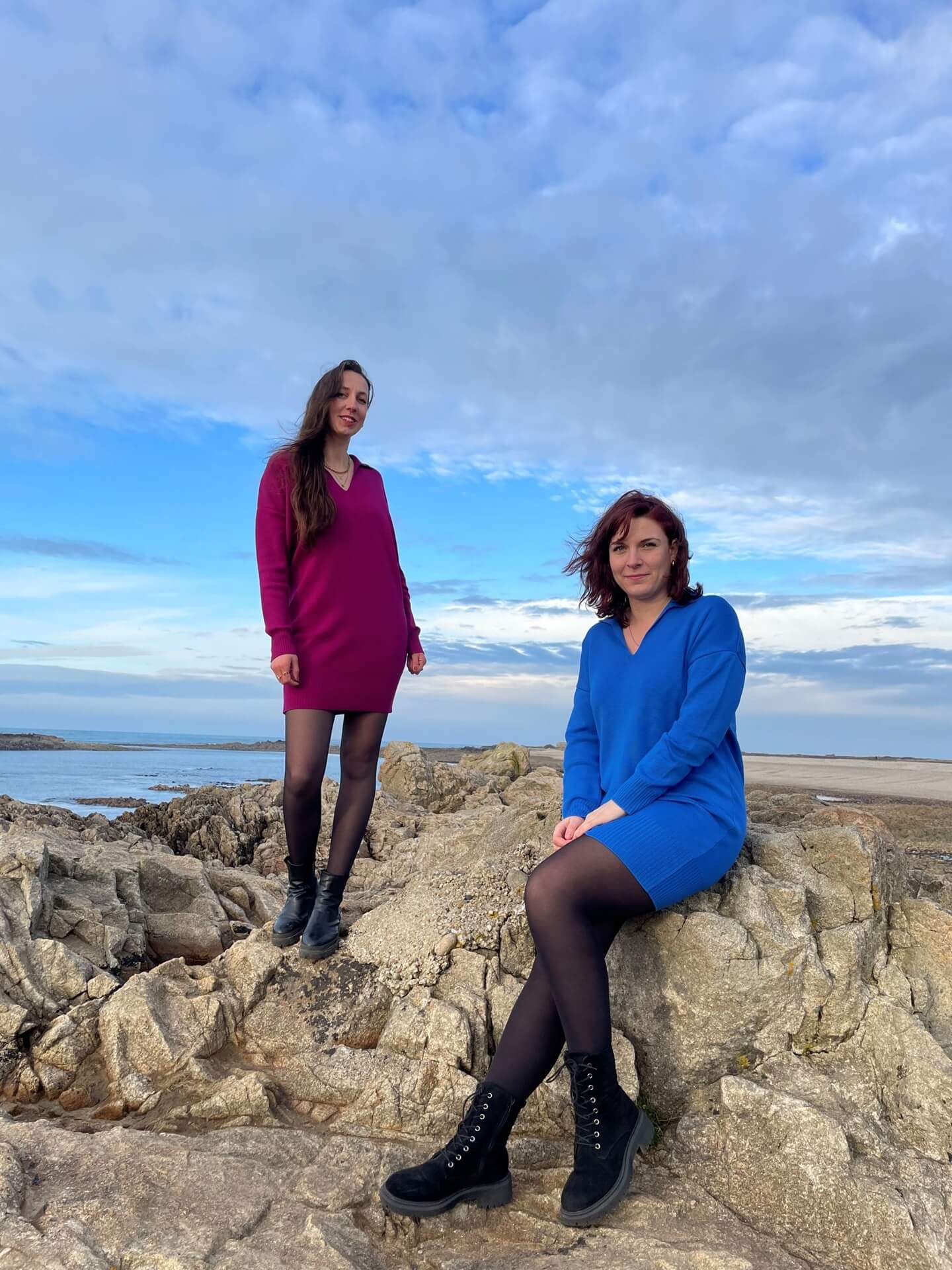 Robes en mérinos extrafin portées par deux femmes. La première, sur la gauche, debout sur un rocher portant la robe en couleur prune. Et une deuxième, sur la droite, assise sur un rocher portant la robe de couleur cobalto.